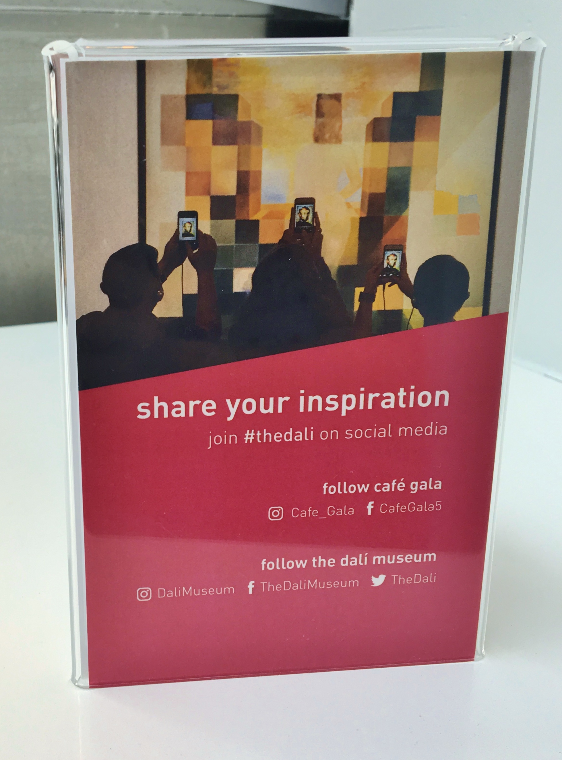 Another insert, this one with a red background and an image of three people taking a picture of one of Dali's paintings with their phones. The text encourages readers to share their pictures from the Museum on social media with the company's hashtags.